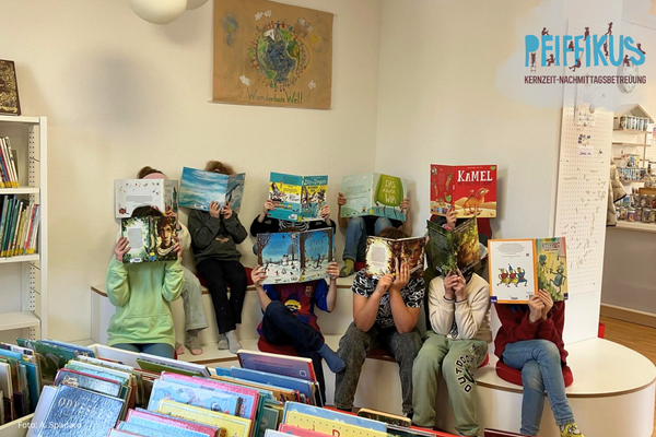 Kinder aus der Kernzeit mit B&uuml;chern vor dem Gesicht 