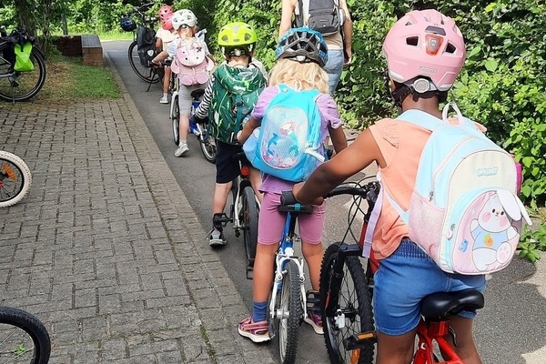 Kinder des Kindergartens Sonnenwinkel stehen mit ihren Fahrr&auml;dern in einer Reihe auf einem Weg